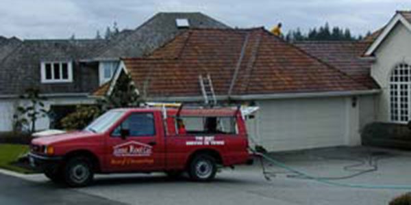 image of alpine roof care truck in front of garage getting its roof clean