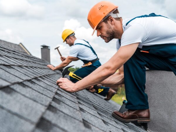 selective focus of handsome handyman repairing roof with coworker selective focus of handsome handyman repairing roof with coworker